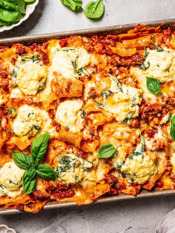 Overhead view of a cheesy sheet pan lasagna garnished with fresh basil leaves.