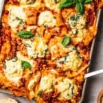 Overhead view of a cheesy sheet pan lasagna garnished with fresh basil leaves.