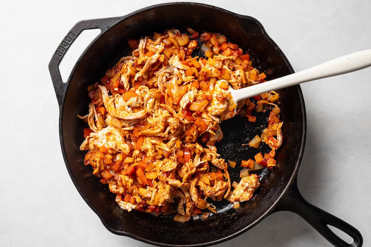 Cooked chicken empanada filling in a skillet.