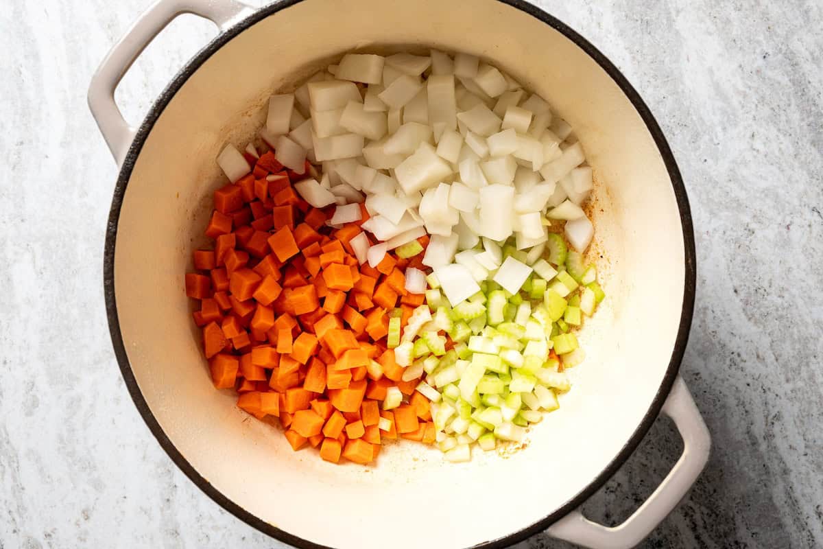 This slow-braised pork ragu recipe cooks for hours in the oven until fall-apart tender and ready to shred into a rich, flavorful meat sauce. Diced vegetables added to a pot to make soffrito.