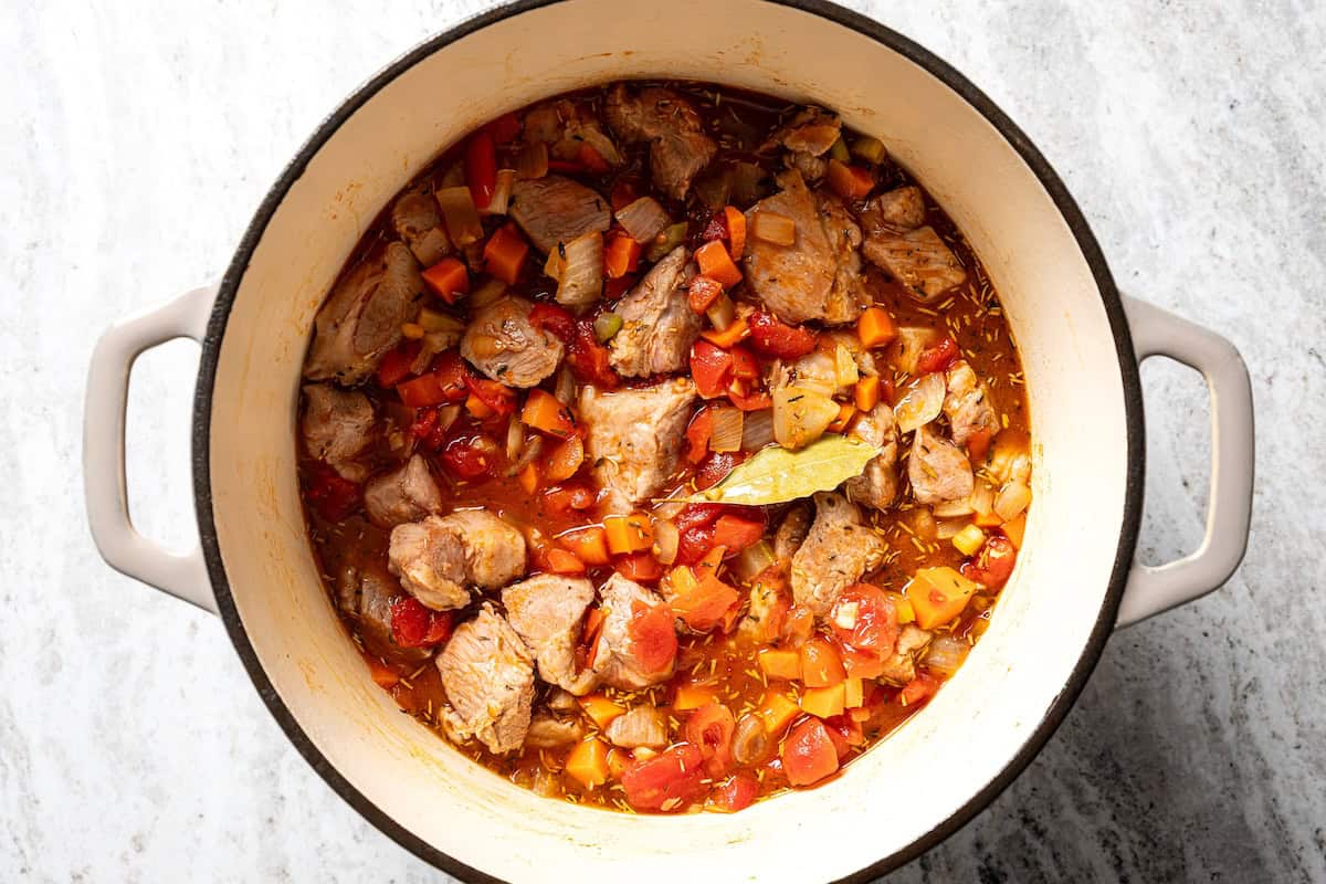 This slow-braised pork ragu recipe cooks for hours in the oven until fall-apart tender and ready to shred into a rich, flavorful meat sauce. Pork ragu ingredients combined in a large pot.
