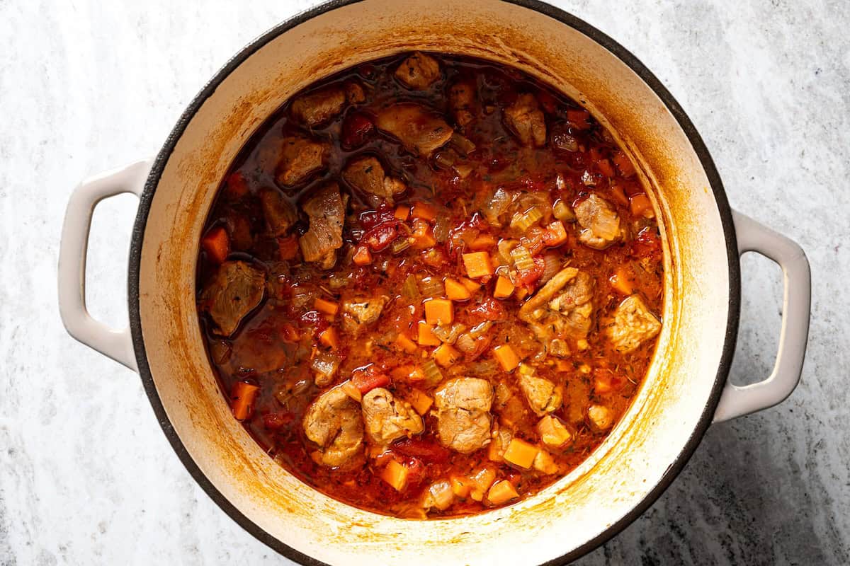 This slow-braised pork ragu recipe cooks for hours in the oven until fall-apart tender and ready to shred into a rich, flavorful meat sauce. Cooked pork ragu in a large pot.