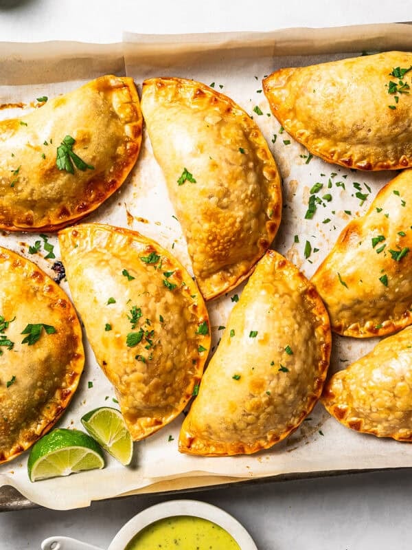 Chicken empanadas arranged on a baking sheet.