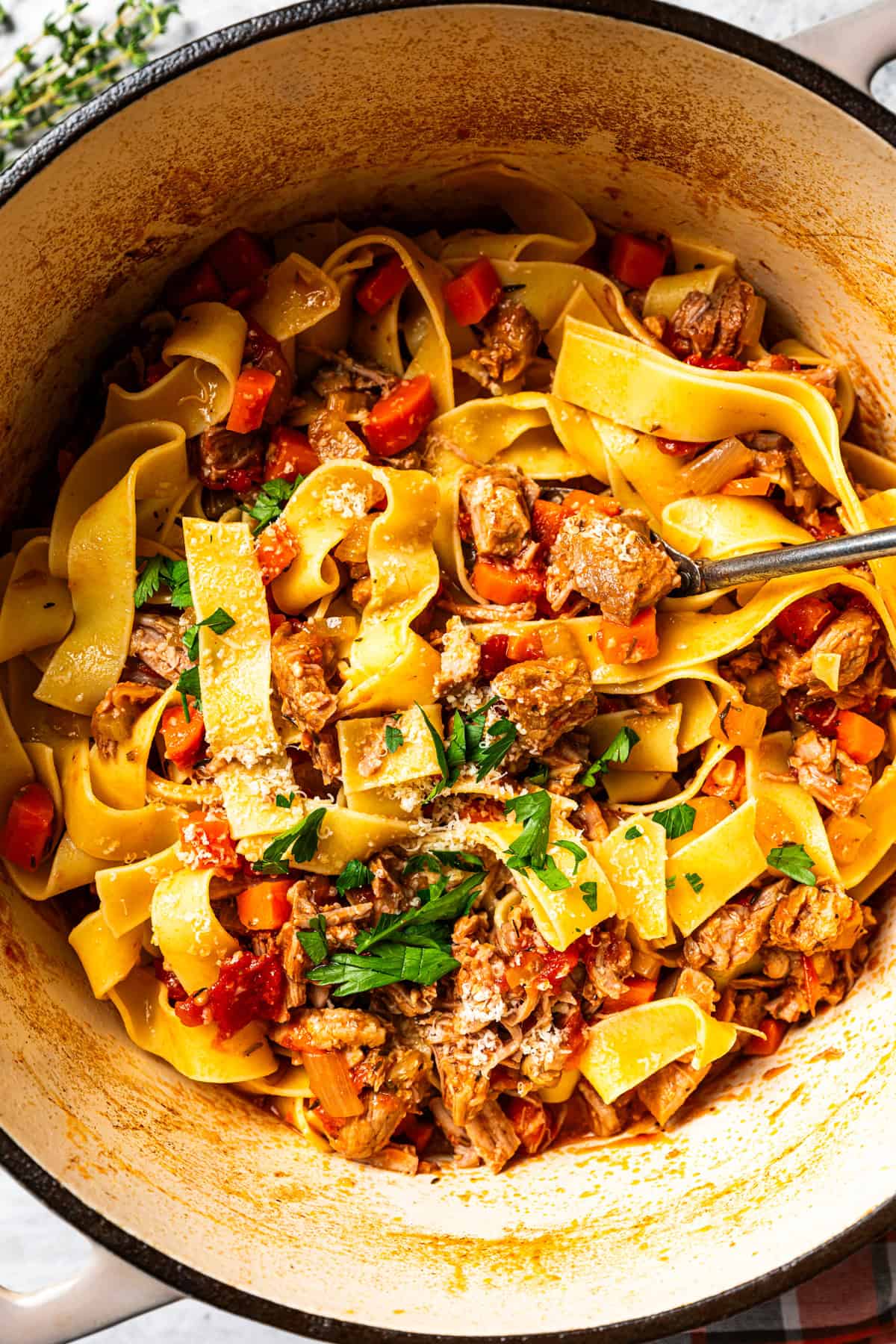 This slow-braised pork ragu recipe cooks for hours in the oven until fall-apart tender and ready to shred into a rich, flavorful meat sauce. Pork ragu with pappardelle pasta, carrots, and tomatoes, in a Dutch oven.