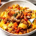 Pappardelle pasta topped with slow-cooked pork ragu, vegetables, Parmesan, and fresh herbs.