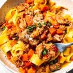 A bowl of pappardelle tossed with homemade pork ragu, garnished with Parmesan and fresh thyme.