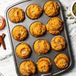 Freshly baked protein pumpkin muffins in a muffin pan topped with coarse sugar.
