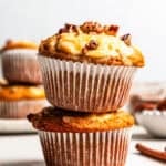 Two pumpkin cream cheese muffins stacked on a countertop.