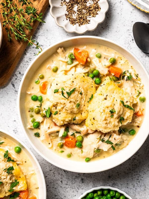 Slow cooker chicken and dumplings served in bowls with tender chicken, carrots, peas, and fluffy homemade dumplings.