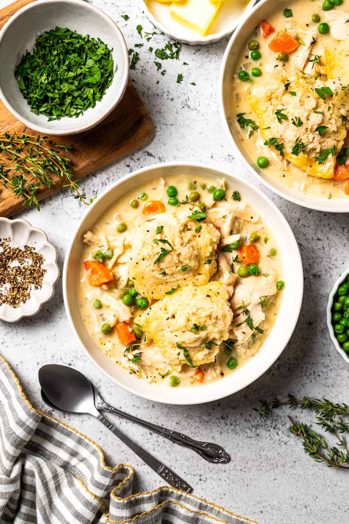 This slow cooker chicken and dumplings recipe is a cozy, creamy chicken stew loaded with homemade biscuit dumplings. All cooked in one pot! Bowls of homemade chicken and dumplings with peas, carrots, chicken, and fresh herbs.