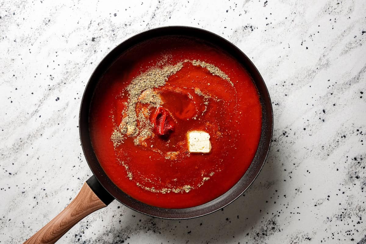 Not your old-fashioned porcupine meatballs! Make these with juicy ground beef, sausage, rice, and herbs, cooked in homemade tomato sauce. Garlic parmesan tomato sauce ingredients combined in a skillet.