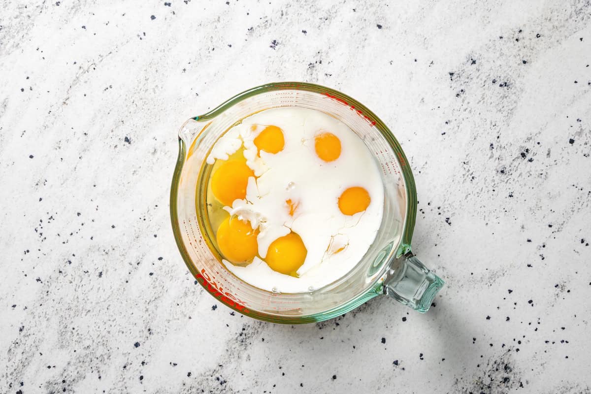 Sheet pan breakfast burritos are an easy way to batch-make breakfast burritos! Bake the filling in one pan, then roll it into soft tortillas. Eggs and milk combined in a glass measuring cup.