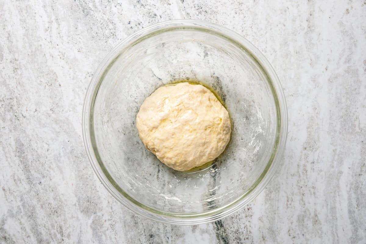 Make this golden, crispy sheet pan pizza recipe with easy homemade dough and your favorite flavorful toppings, like pepperoni and cheese. A smooth pizza dough ball in a mixing bowl.