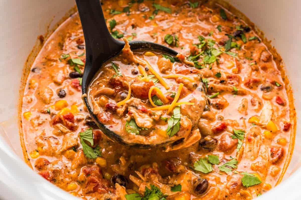 Thick and creamy Buffalo chicken chili made with shredded chicken, beans, Buffalo sauce, and cream cheese. An easy crockpot chili, perfect for weeknights or game day! Ladling out chicken chili from the slow cooker.