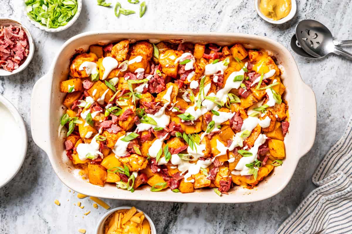 This chicken potato casserole combines juicy seasoned chicken and potatoes, baked in one pan and loaded with bacon, cheese, and sour cream. Chicken potato casserole in a baking dish topped with bacon, shredded cheese, green onions, and sour cream.