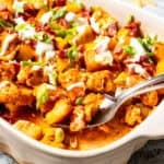 A serving spoon scooping out potatoes from a casserole dish.