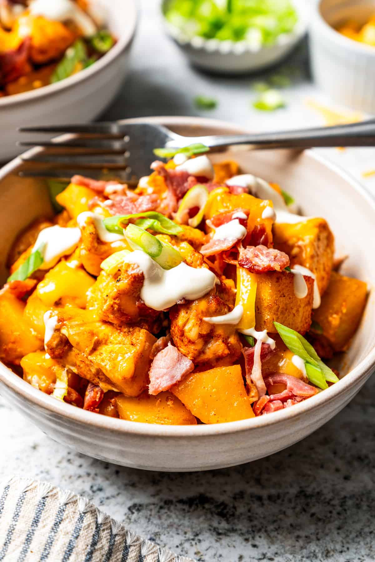 This chicken potato casserole combines juicy seasoned chicken and potatoes, baked in one pan and loaded with bacon, cheese, and sour cream. A serving of chicken potato casserole in a bowl with a fork.