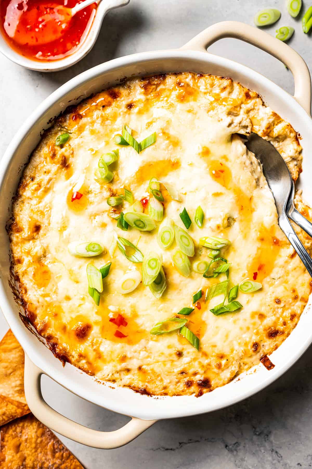 Crab rangoon dip has all those creamy flavors in an easy baked crab dip with cream cheese, sweet chili, green onion, and crispy wonton chips. Homemade crab rangoon dip in a small casserole dish.