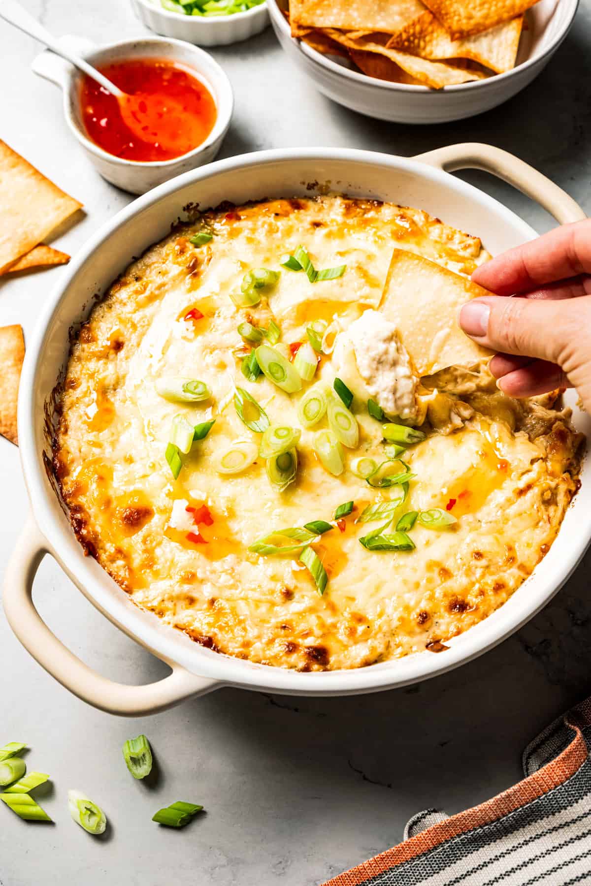 Crab rangoon dip has all those creamy flavors in an easy baked crab dip with cream cheese, sweet chili, green onion, and crispy wonton chips. Baked homemade crab rangoon dip with green onions and sweet chili sauce, served with crispy wonton chips for scooping.