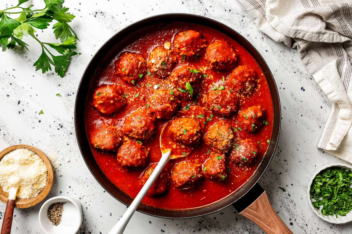 Not your old-fashioned porcupine meatballs! Make these with juicy ground beef, sausage, rice, and herbs, cooked in homemade tomato sauce. Homemade porcupine meatballs simmering in a tomato sauce in a skillet, garnished with fresh parsley and grated Parmesan cheese.