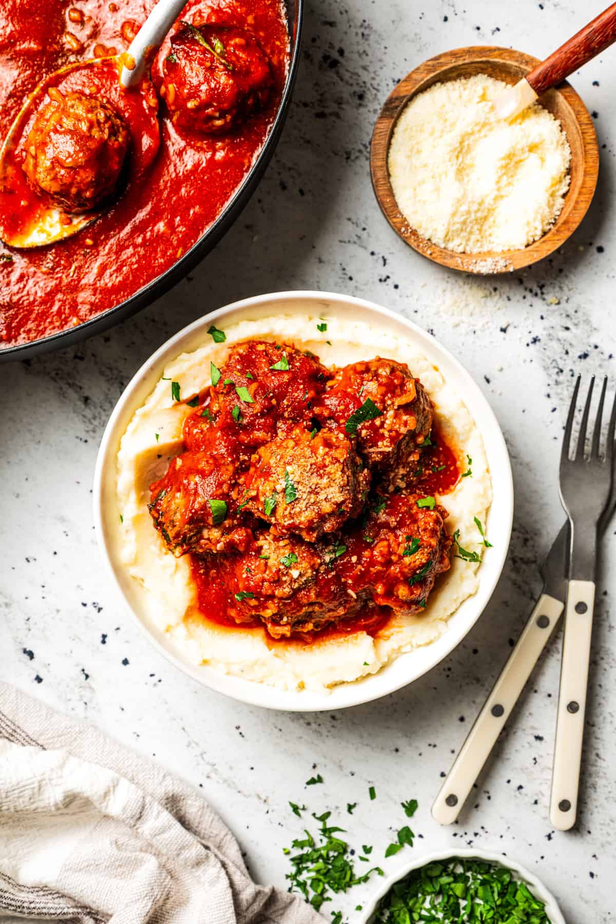 Not your old-fashioned porcupine meatballs! Make these with juicy ground beef, sausage, rice, and herbs, cooked in homemade tomato sauce. A plate of porcupine meatballs smothered in tomato sauce and served over creamy mashed potatoes.