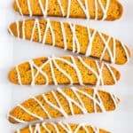 Close-up of crisp pumpkin biscotti topped with cinnamon sugar and white chocolate drizzle.