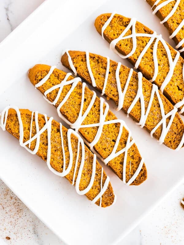 Pumpkin biscotti drizzled with white chocolate arranged on a serving platter.