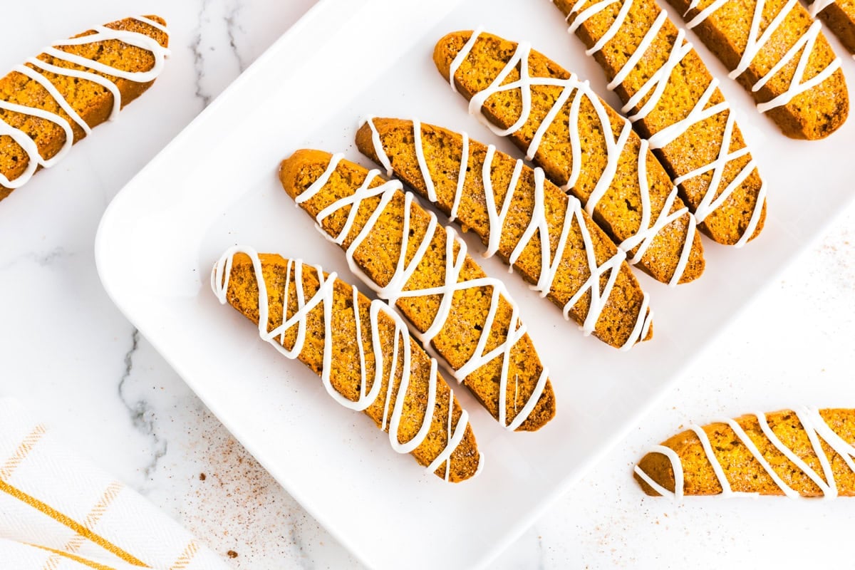 Pumpkin biscotti drizzled with white chocolate arranged on a serving platter.