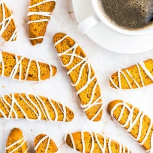 Pumpkin biscotti drizzled with white chocolate and served with a cup of coffee.