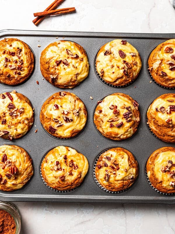 Freshly baked pumpkin cream cheese muffins in a muffin pan.