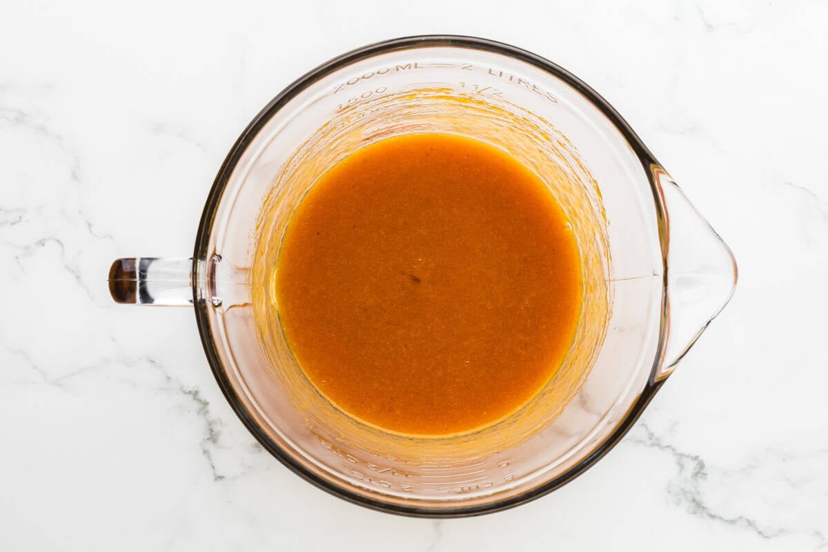 Pumpkin puree mixture in a large glass cup, prepped for pumpkin biscotti dough.