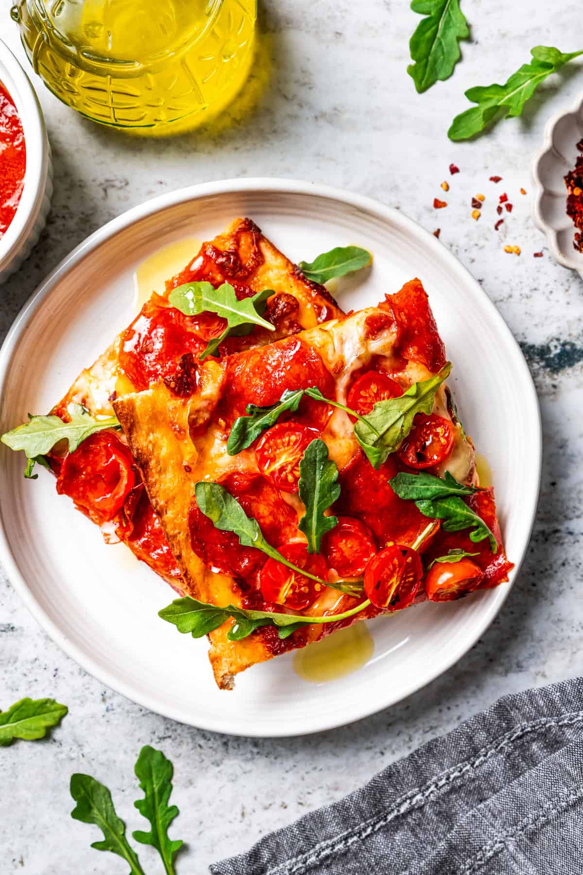 Make this golden, crispy sheet pan pizza recipe with easy homemade dough and your favorite flavorful toppings, like pepperoni and cheese. Two square slices of pizza served on a plate.