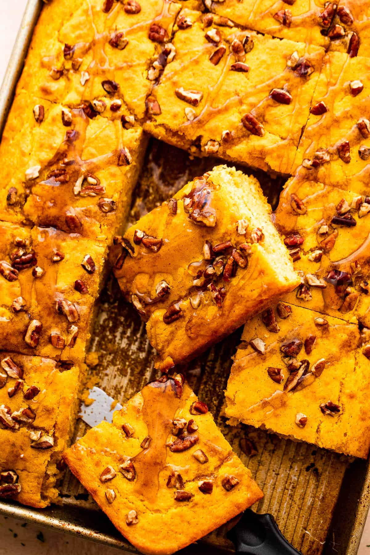 Weekly Meal Plan Sheet pan pumpkin pancakes cut into squares, topped with chopped pecans and a drizzle of maple syrup, with two pieces pulled away to show their fluffy texture.